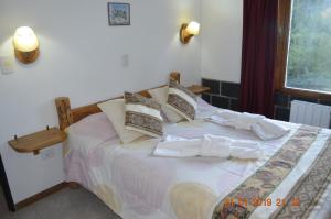 Schlafzimmer mit einem Bett mit weißer Bettwäsche und Kissen in der Unterkunft Apart Bungalows Amulen in San Carlos de Bariloche