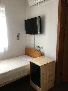 a small room with a bed and a flat screen tv at Makk Marci Panzió in Tokaj