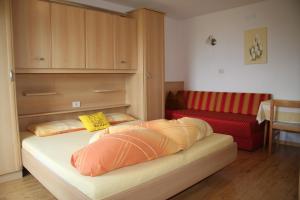 Habitación con cama y sofá rojo en Mair am Hof - Farm - Maso - Bauernhof, en San Lorenzo di Sebato
