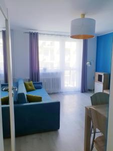 ein Wohnzimmer mit einem blauen Sofa vor einem Fenster in der Unterkunft Apartament Wałbrzych in Wałbrzych