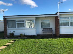 a white house with a bench in the window at 314 Sundowner in Hemsby