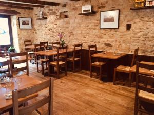 a restaurant with wooden tables and chairs and a stone wall at Auberge du Lac in Mandailles