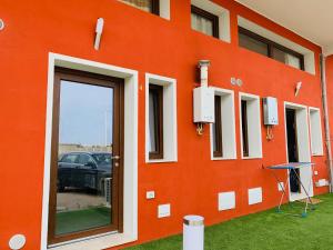 a building with an orange wall with a door at Luxar room in Assemini