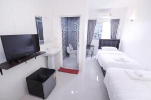 a white room with two beds and a flat screen tv at U-need Guesthouse95 in Bangkok