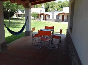 eine Terrasse mit einem Tisch, Stühlen und einer Hängematte in der Unterkunft Cabañas Jacy in Tafí del Valle