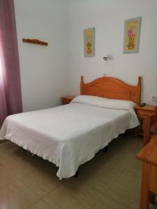 sypialnia z białym łóżkiem z drewnianym zagłówkiem w obiekcie Hostal Sierpes w Sewilli
