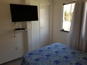 a bedroom with a bed and a flat screen tv at Apto na Praia de Guaibim in Guaibim