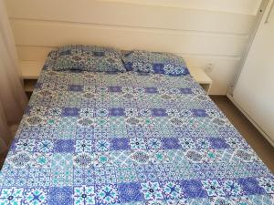 a bed with a blue and white quilt on it at Apto na Praia de Guaibim in Guaibim