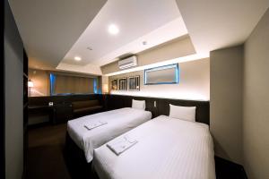 京都市にある京都糸屋ホテルのベッド2台とデスクが備わるホテルルームです。
