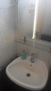 lavabo blanco en el baño con espejo en Hajni apartman, en Vonyarcvashegy