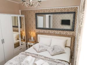 a bedroom with a white bed and a mirror at YNS Apartaments in Iaşi
