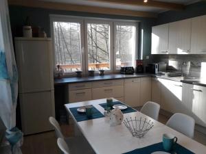 a kitchen with a white table and chairs and windows at Bobrowa Przystań in Czechyń