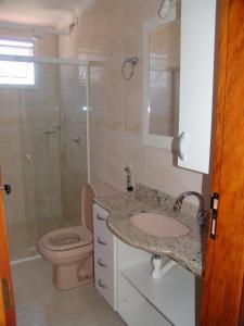 a bathroom with a toilet and a sink and a shower at Condomínio Pedra Coral in Ubatuba