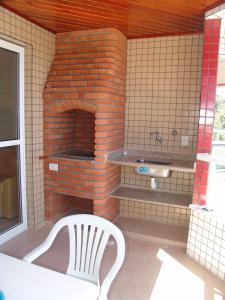 a brick oven with a white chair in front of it at Condomínio Pedra Coral in Ubatuba