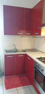a kitchen with red cabinets and a sink at Ladybug Apartment in Poggibonsi