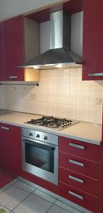 a kitchen with red cabinets and a stove top oven at Ladybug Apartment in Poggibonsi