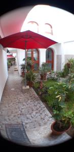 a red umbrella on a walk way with plants at Residencial Maria Bonita in Paracas