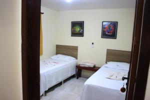 a room with two beds and two pictures on the wall at Pousada Casa da Gente in Caruaru