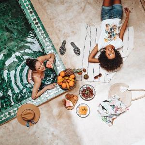 dwie dziewczyny leżące obok basenu z jedzeniem w obiekcie Riad SHIRAZ w Marakeszu