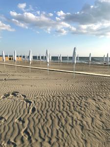 a sandy beach with white umbrellas and the ocean at Il Miraggio in Fregene