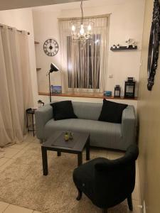 uma sala de estar com um sofá, uma mesa e um relógio em CHARMANT T2 PROCHE CENTRE VILLE PLAGE JARDIN DIOR 50 m2 em Granville