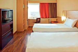 a hotel room with two beds and a television at ibis Sao Paulo Interlagos in Sao Paulo