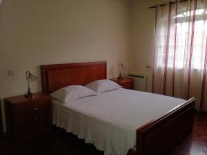 um quarto com uma cama grande com lençóis brancos e uma janela em Casa dos Laços em Viseu