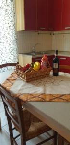 a basket of fruit on a table with a bottle of wine at Ladybug Apartment in Poggibonsi