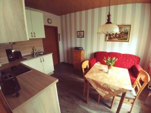 a small kitchen with a table and a red couch at Ferienwohnung Schwantje in Aurich