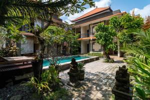 a house with a swimming pool in a garden at Eddys Cottages & Villa in Legian