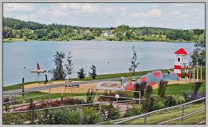 a view of a lake with a playground and a lighthouse at Bungalow direkt am Wasser in Stelzendorf