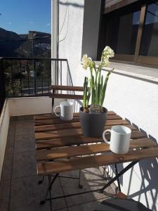 een houten tafel met kopjes en een plant op een balkon bij APARTAMENTO LOS NARCISOS in Chulilla