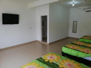 a room with two beds and a flat screen tv at Hotel Villa Marán Chachalacas Ambiente Familiar in Chachalacas