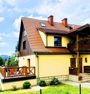 a yellow house with a red roof at Apartament Ginger in Kudowa-Zdrój