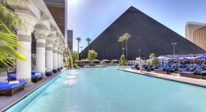 
a swimming pool with a large blue umbrella in front of it at Luxor in Las Vegas
