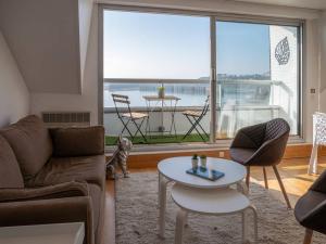 a living room with a couch and a table and a large window at UN BALCON SUR LA MER, ACCES DIRECT A LA PLAGE in Granville