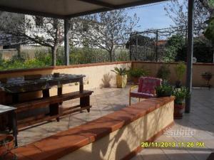 een patio met een houten bank en een stoel bij Bungalow a Triscina di Selinunte in Triscina