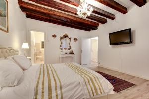a bedroom with a white bed and a flat screen tv at Ca' Invidia in Venice