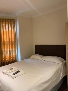 1 dormitorio con 1 cama con sábanas blancas y control remoto. en City Lodge London, en Londres