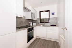 Una cocina blanca con gabinetes blancos y una ventana. en No. 6 Apartment, en Inverness 3 fotos más