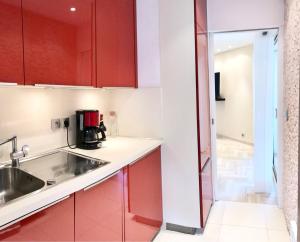 eine Küche mit roten Schränken und einem Waschbecken in der Unterkunft 19 Rue du Parc Alexandre III in Cannes