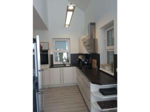 uma cozinha com armários brancos e um balcão preto em Villa Ostseebrise em Trent