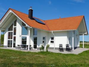 uma casa branca com um telhado laranja e duas cadeiras em Villa Ostseebrise em Trent