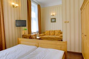 um quarto com uma cama, um sofá e uma televisão em Hotel Štekl - Hrubá Skála em Hrubá Skála