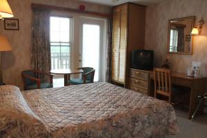 una camera d'albergo con letto, scrivania e TV di Forest Haven Inn a Tatamagouche