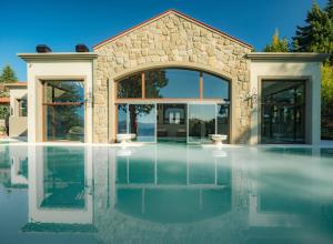 a swimming pool in front of a stone house at Villa Beluno Hotel & Spa in San Carlos de Bariloche