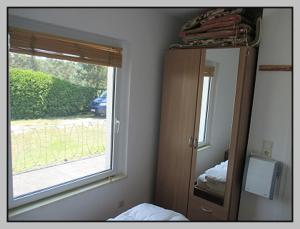 a bedroom with a mirror and a dresser and a window at Bungalow direkt am Wasser in Stelzendorf