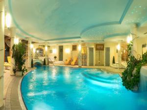 a large blue swimming pool in a building at Wohlfühl & Genusshotel Felsenhof in Bad Kleinkirchheim