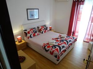 sypialnia z łóżkiem z czerwonym i białym kocem w obiekcie Apartments Šime w mieście Dinjiška