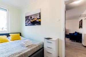 a bedroom with a bed with yellow pillows and a desk at Apartamenty NCNK Leśny Zaułek Sztutowo in Sztutowo